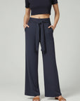 Silvorne navy blue wide-leg trousers with tied waistband and pockets, styled casually.