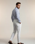 Silvorne men's white high-waist straight-leg draped trousers made from premium woven fabric. Model wears with a blue striped shirt and brown loafers.